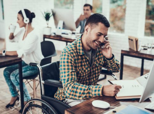 Man on Wheelchair Write Notes and Talking on Phone. Disabled Young Man. Man on Wheelchair. Recovery and Healthcare Concepts. Teamwork in Office. Young Worker. Sitting Man. Talking on Phone.